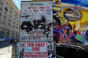 Juxtaposition: a tagged-up sign sits next to an untouched mural on 14th St.